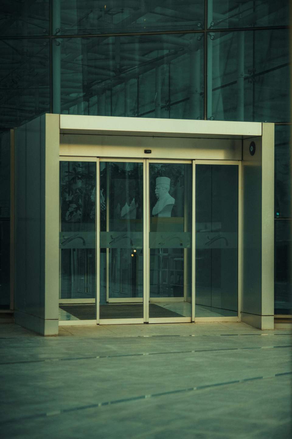 Glass entrance showcasing a modern bust, ideal for architectural and art themes.
